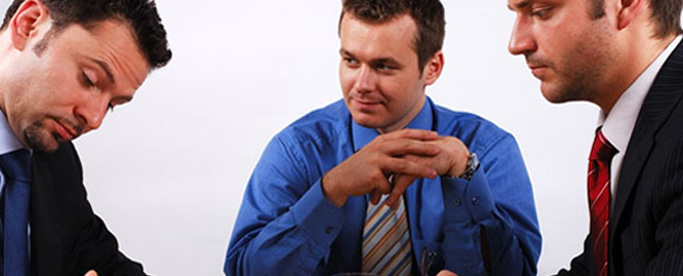 three businessmen having a meeting, one receiving professional advice about commercial finance and doing paperwork